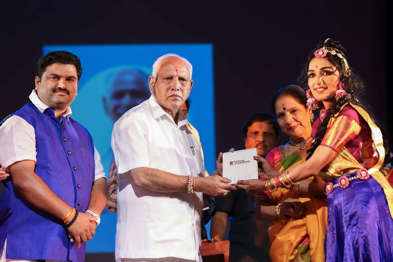 B.S. Yediyurappa releasing the Kailasa Kaladhara calendar on stage with the Guru and a lead dancer